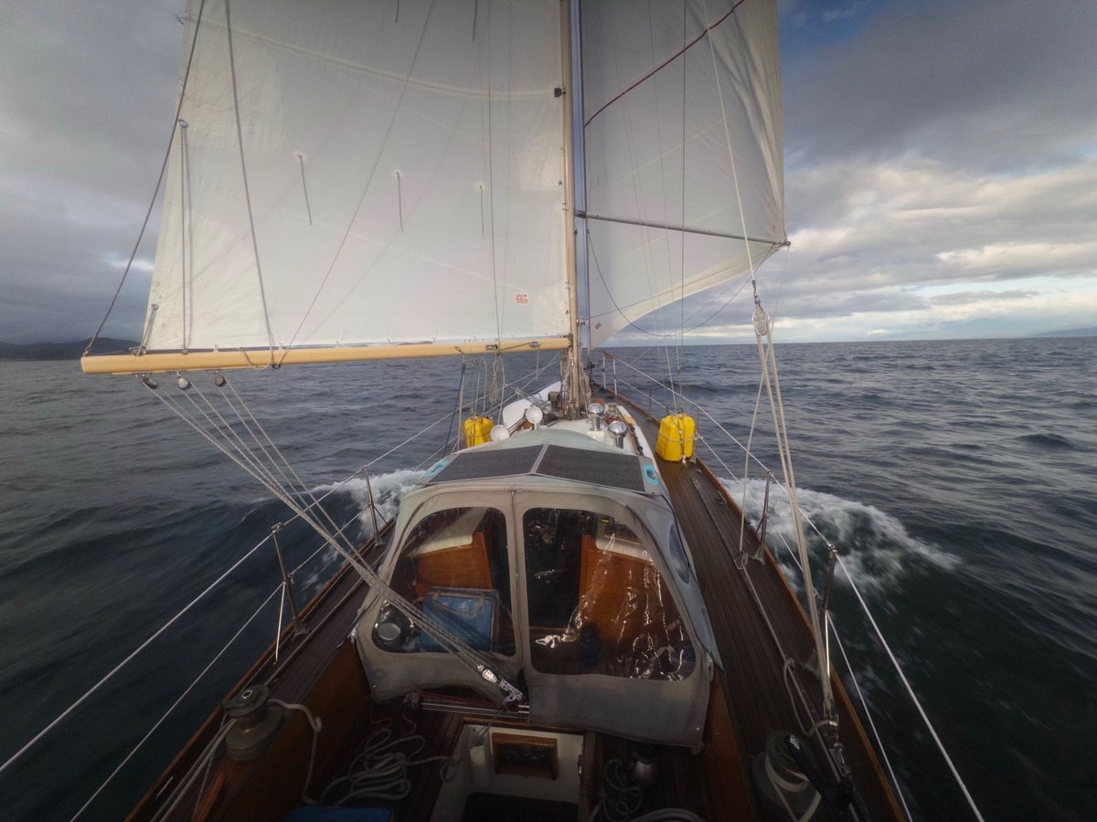 Looking forward from Jura's cockpit under full sail, the bow lifting over grey water